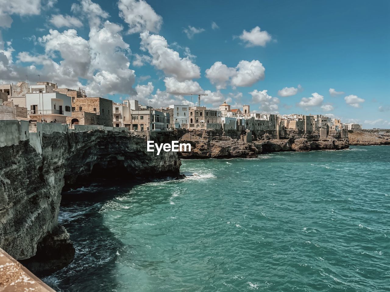 Buildings by sea against sky