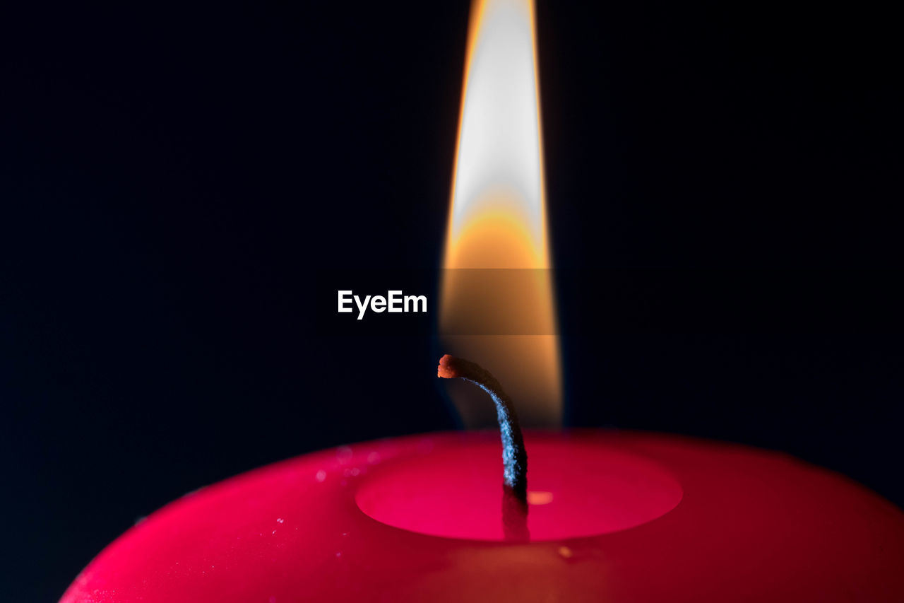 Close-up of lit candle against black background