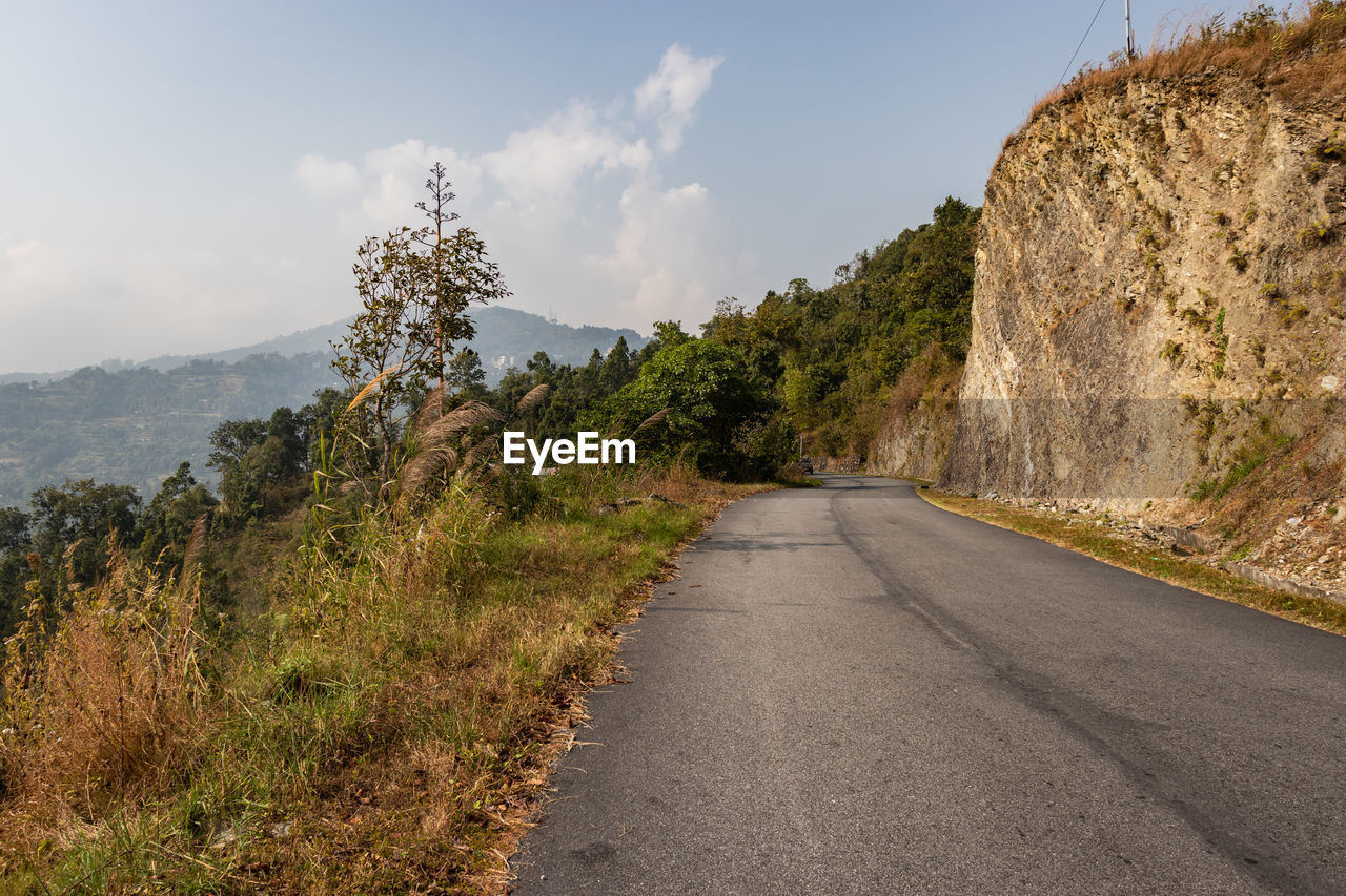 Isolated road amidst trees against sky