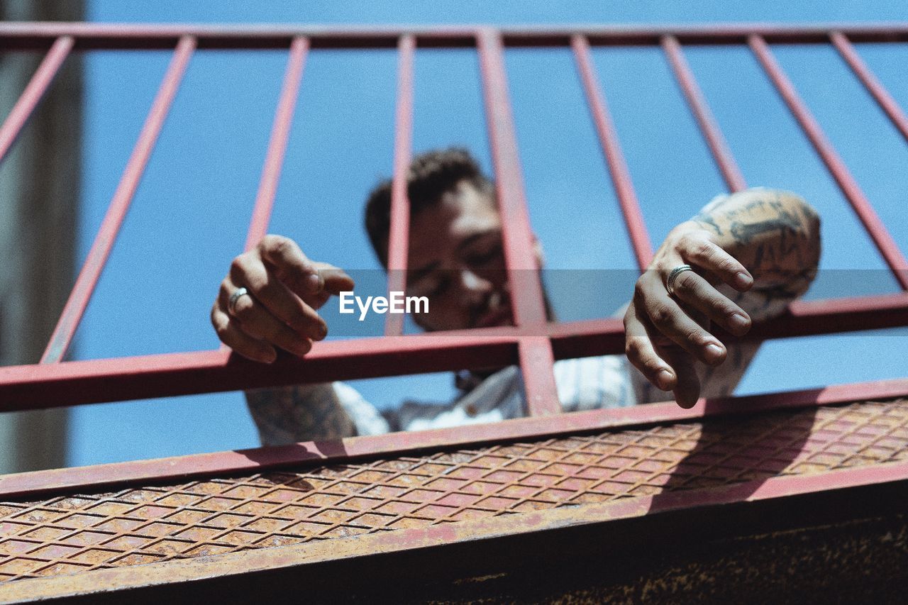 Low angle view of man seen through railing