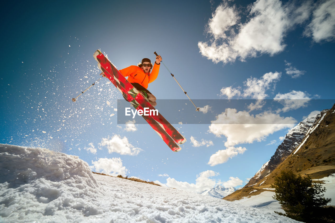 Fly young caucasian man jumping from a springboard on skis