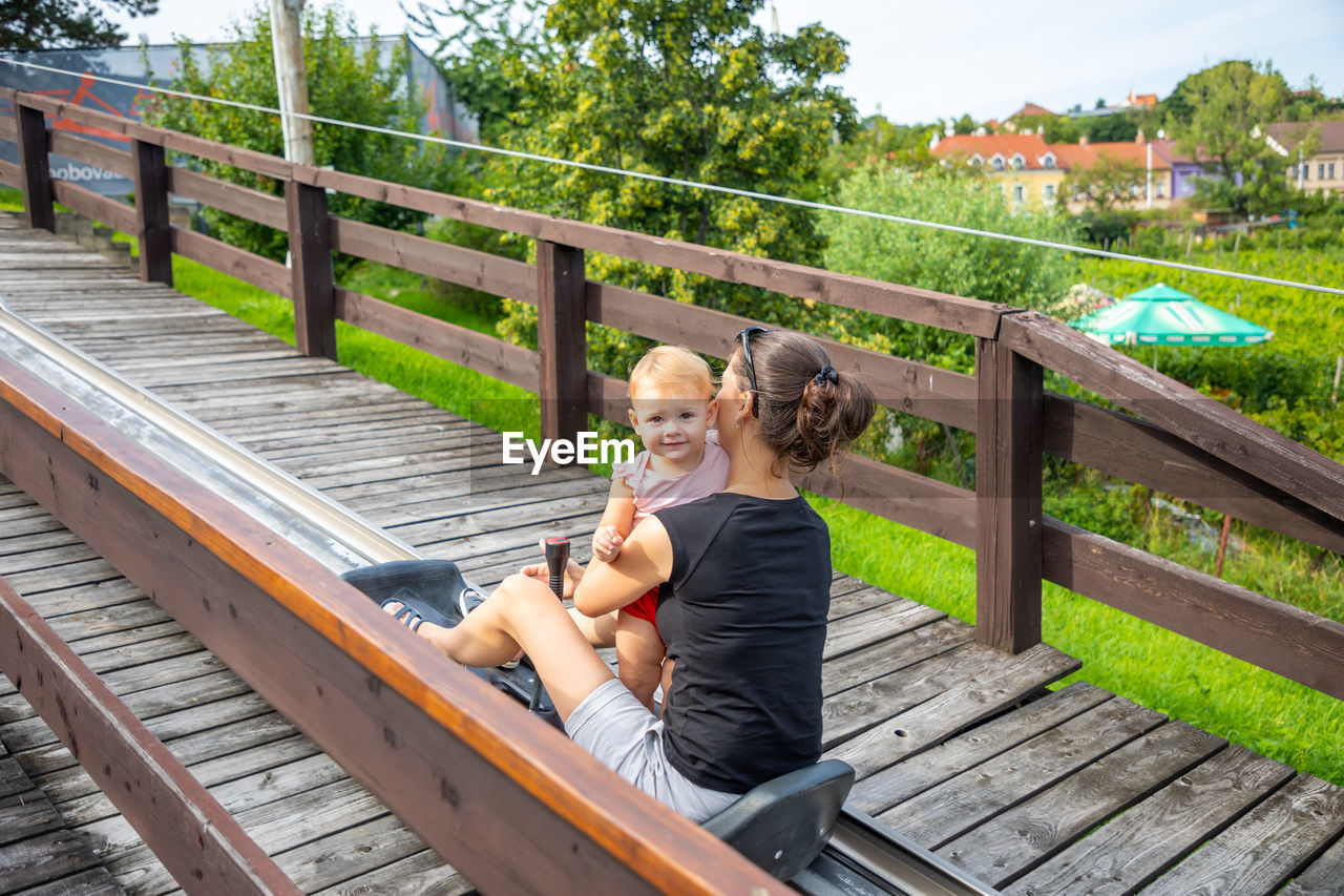 WOMAN SITTING ON BENCH AGAINST FOOTBRIDGE