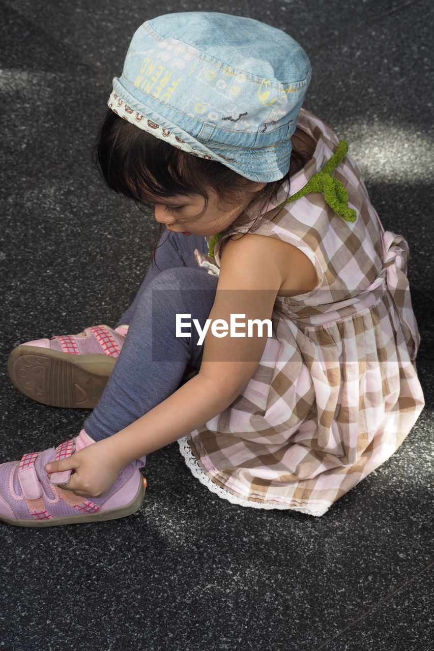 High angle view of girl wearing sandal on road