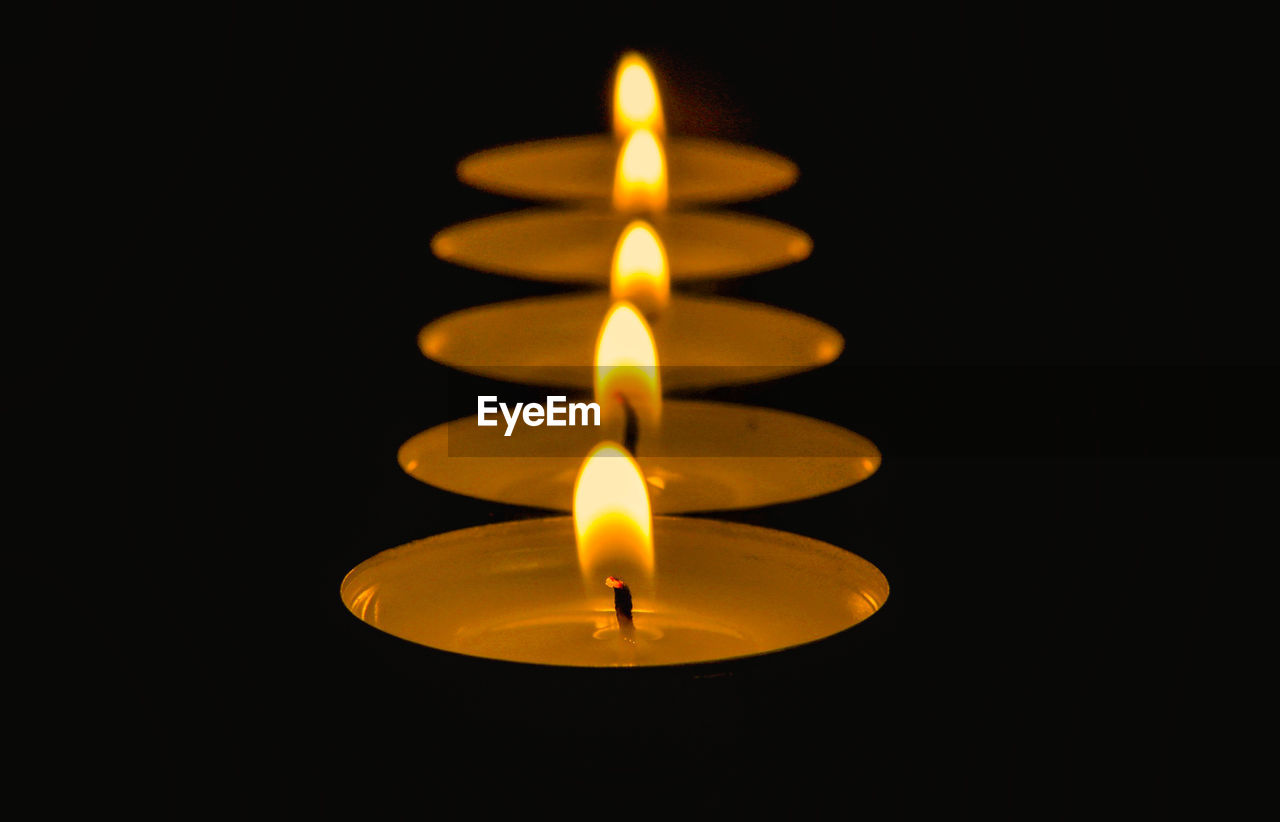 Close-up of illuminated candle over black background