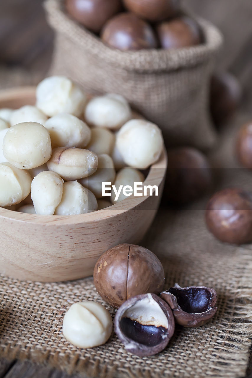 Macadamia nuts on sackcloth and wooden background
