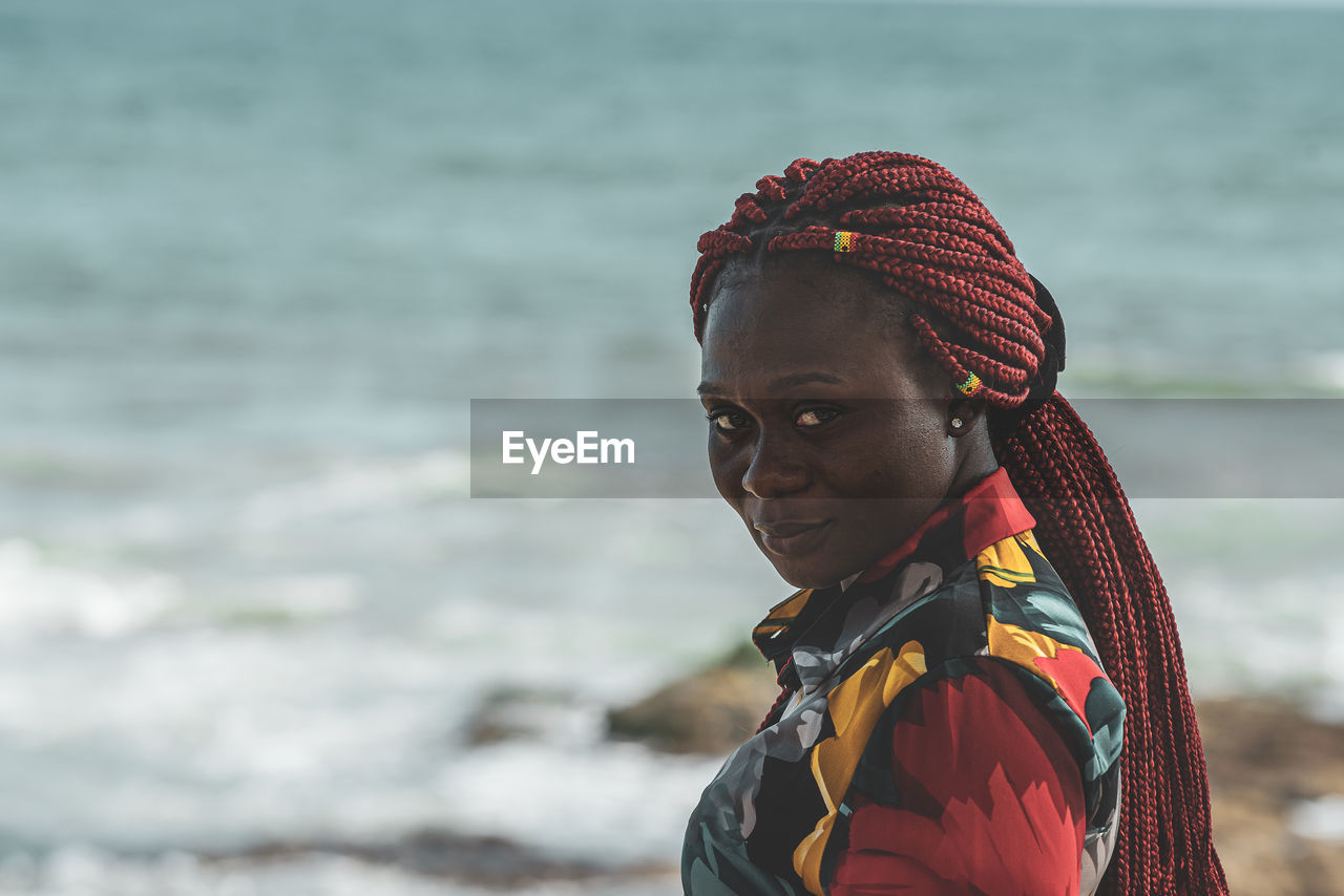 African woman with rasta hair with attached small ghana flags on the accra coast ghana