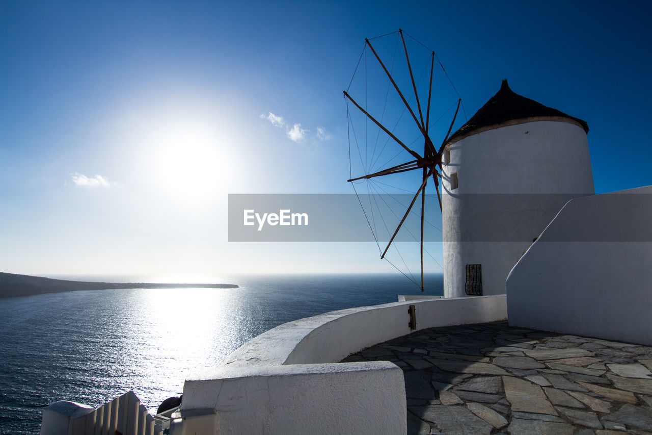 TRADITIONAL WINDMILL BY SEA AGAINST SKY DURING SUNRISE