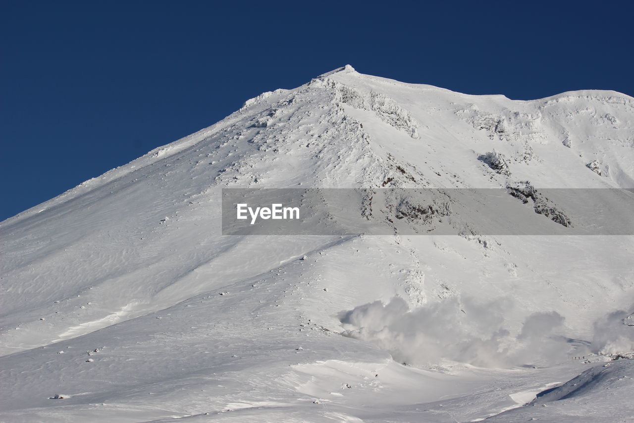 Scenic view of snowcapped mountains against clear blue sky