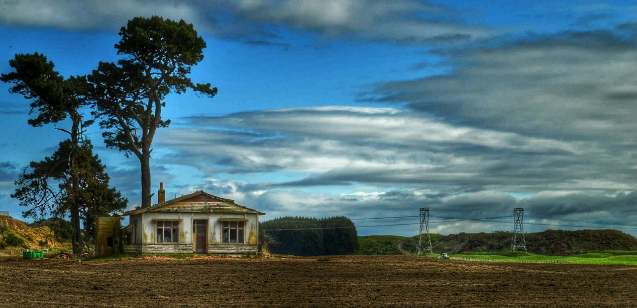 House on field against cloudy sky