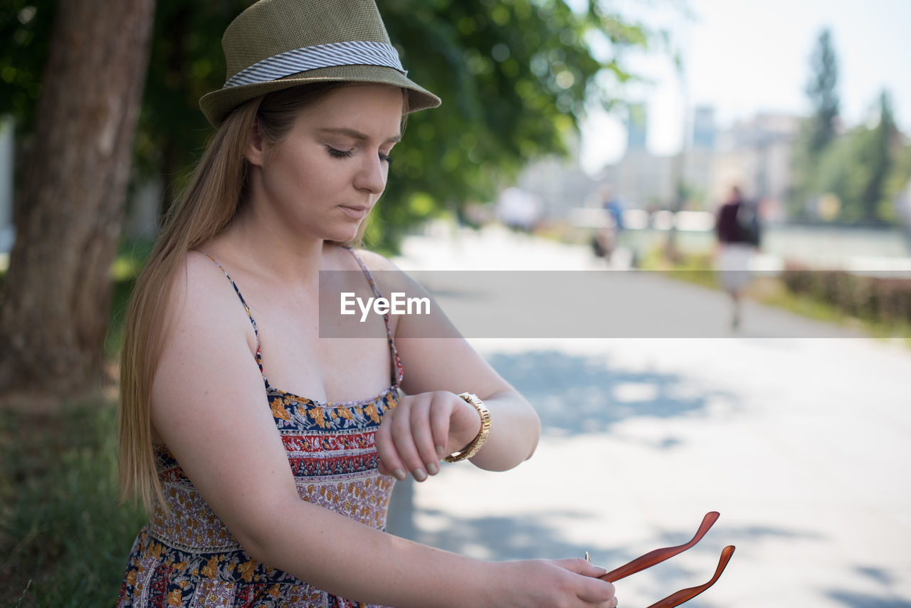 Young woman checking time while sitting at park