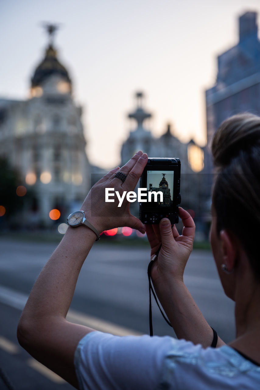 Woman photographing historic building from camera in city