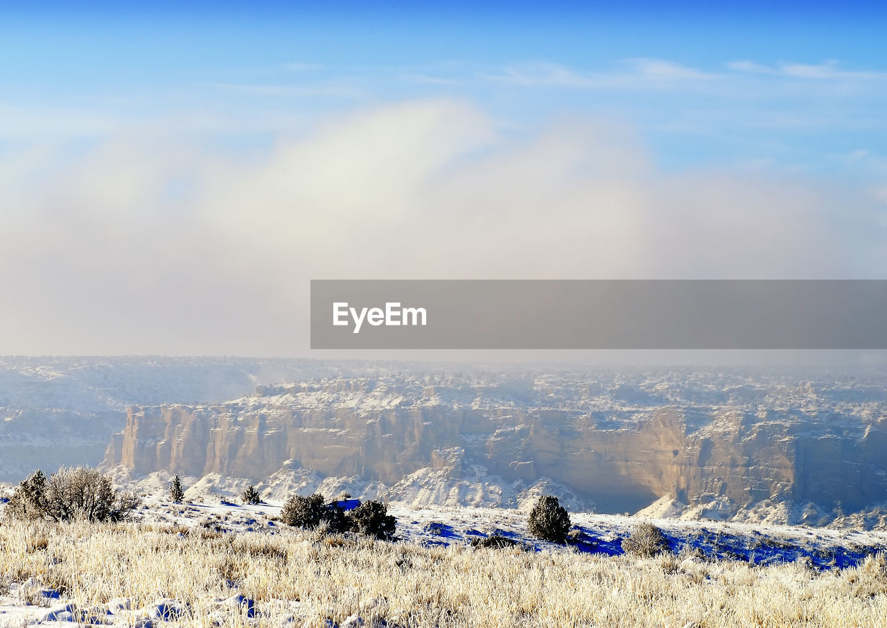 Aerial view of arid landscape with rocky structures against cloudy sky