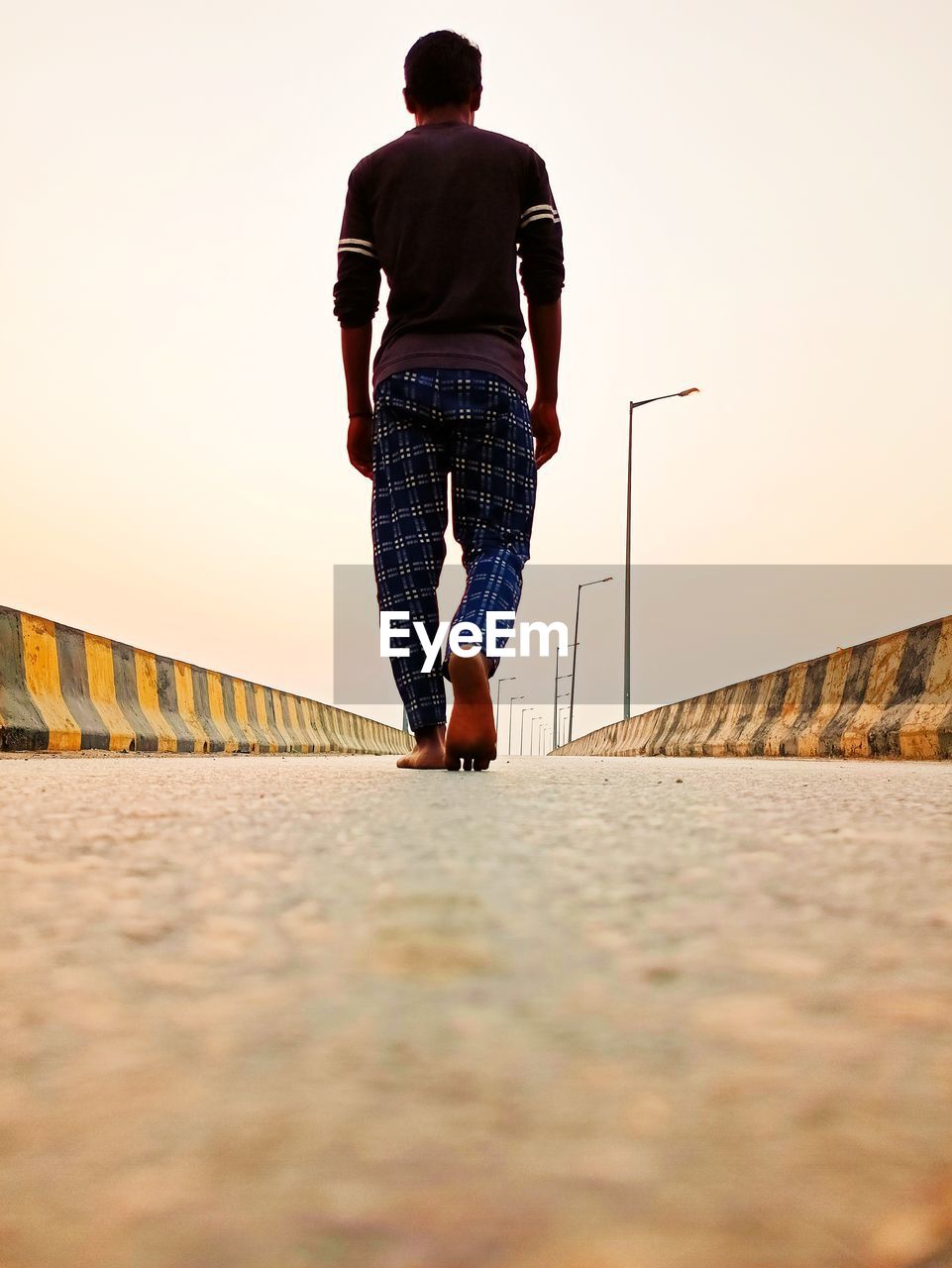 FULL LENGTH REAR VIEW OF MAN WALKING ON BRIDGE