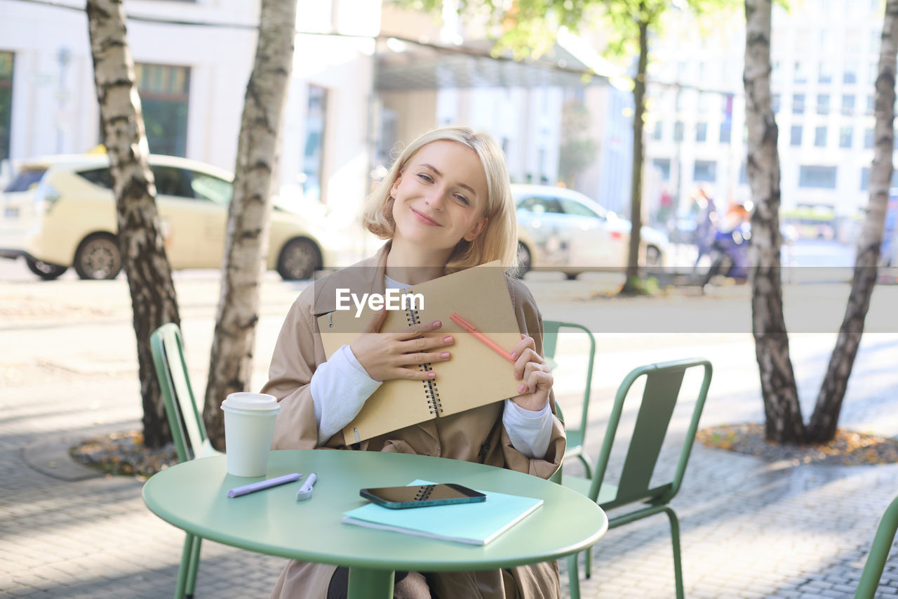 young woman using mobile phone while sitting on chair