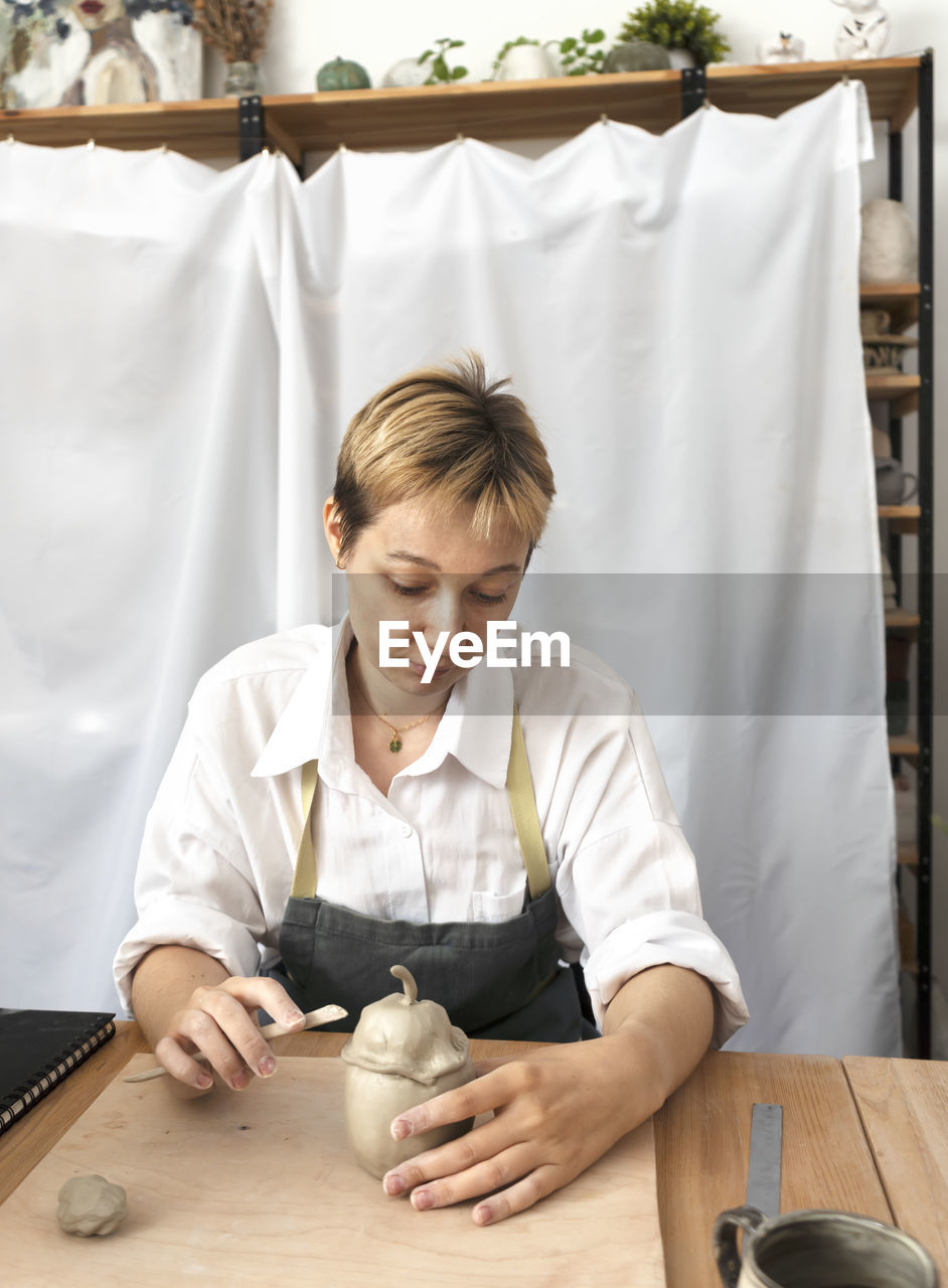 A student learns to sculpt ceramic products from clay. pottery workshop class. artisan production.