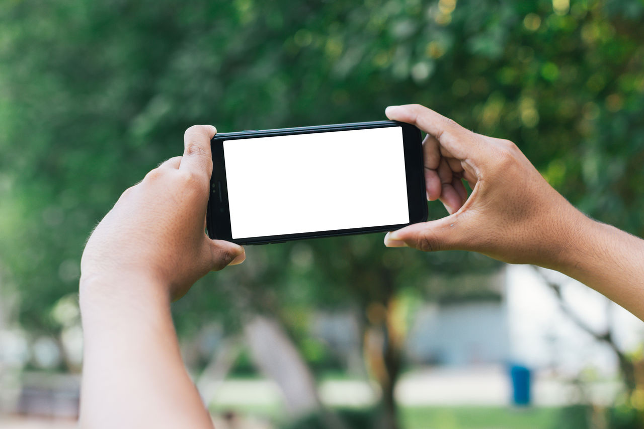 cropped hands using digital tablet outdoors