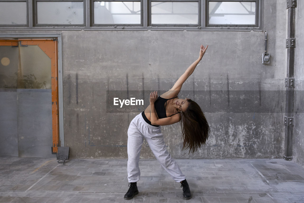 Female dancer practicing against wall in abandoned factory