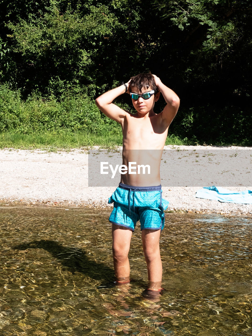 Full length of shirtless boy standing in water