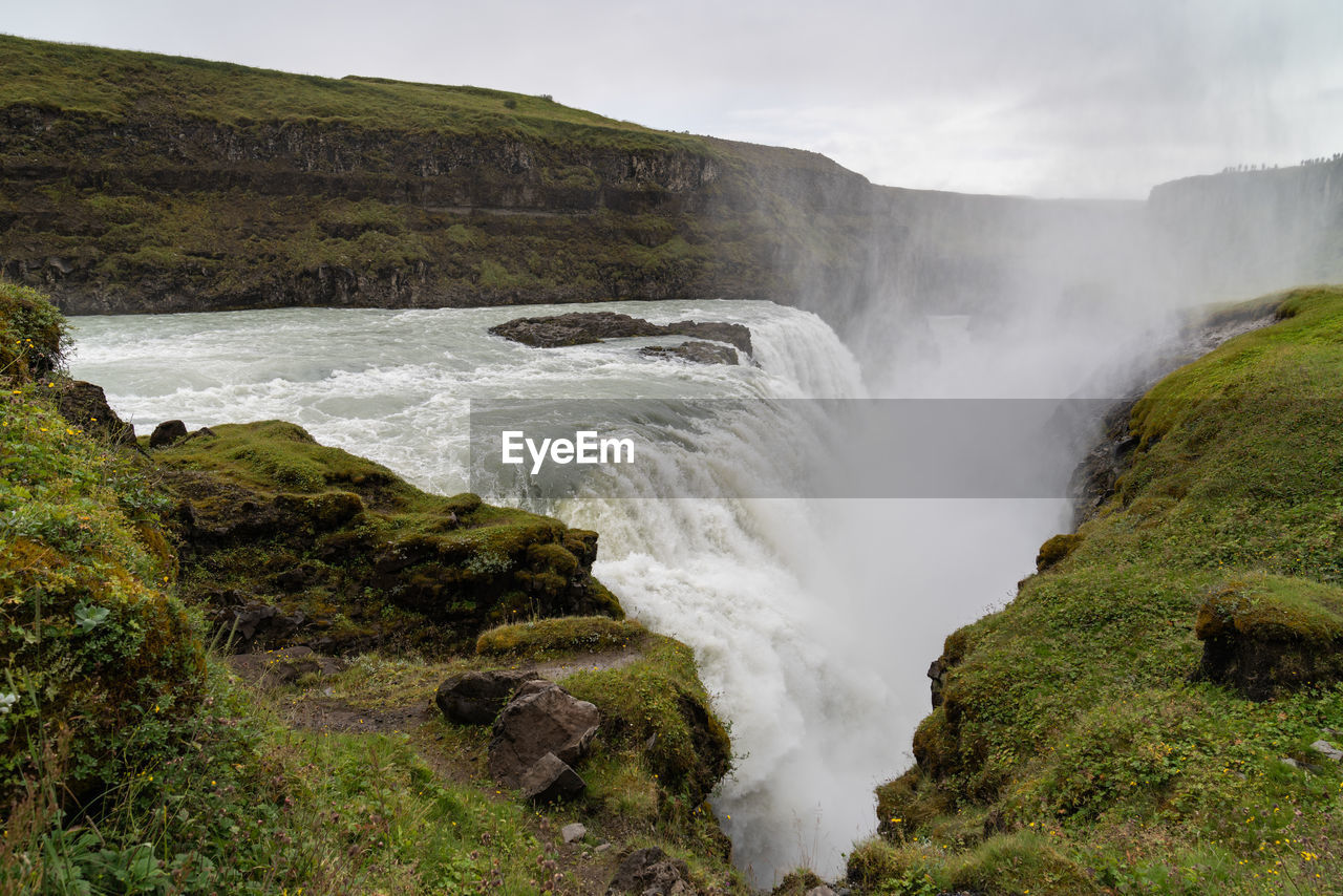 Scenic view of waterfall against sky