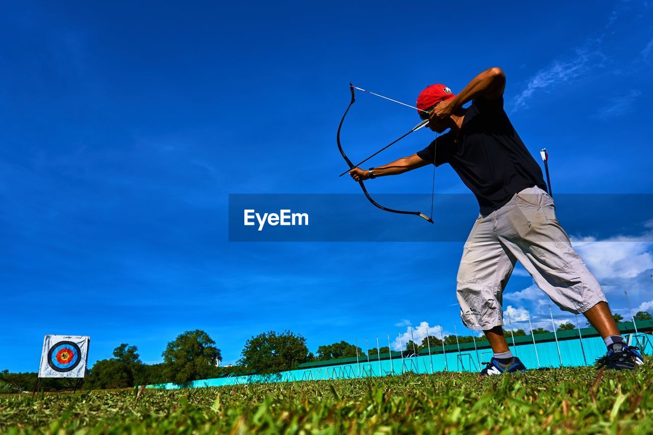 Low angle view of man aiming with bow