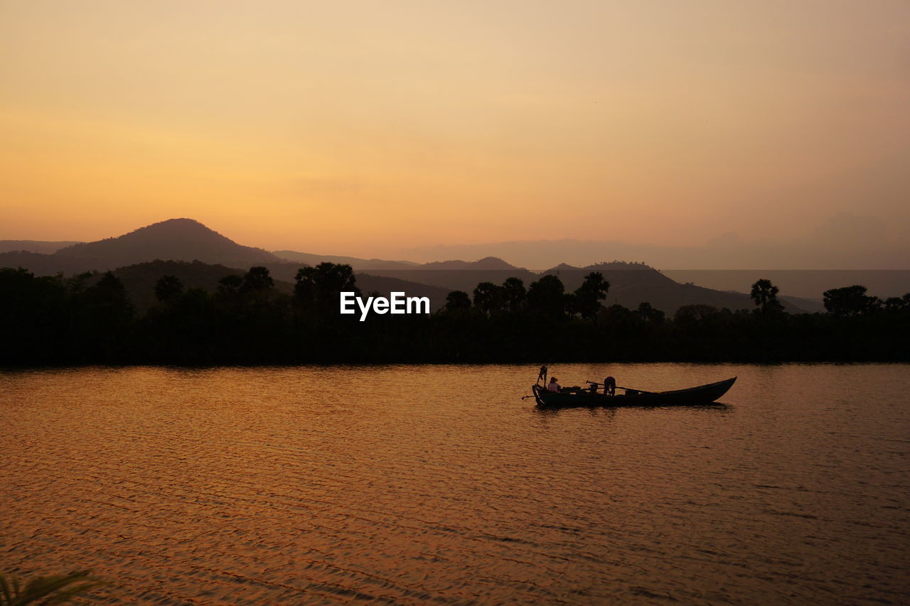 Silhouette boat in lake against sky during sunset