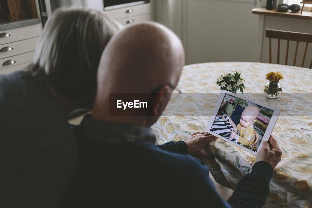 Couple having video chat with baby grandson on tablet