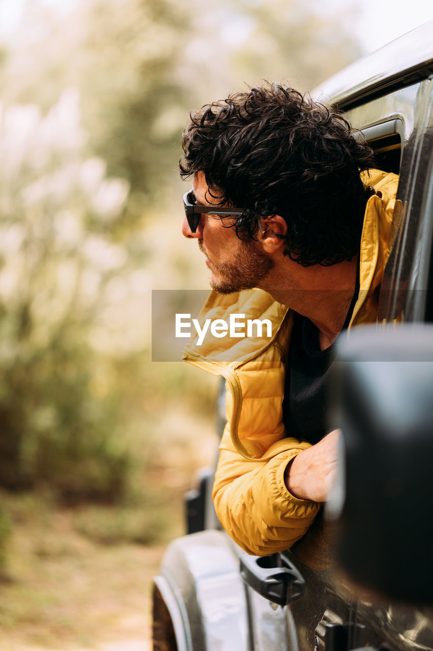 Side view of an adventurer with sunglasses peeking out of the car sale with blurred background