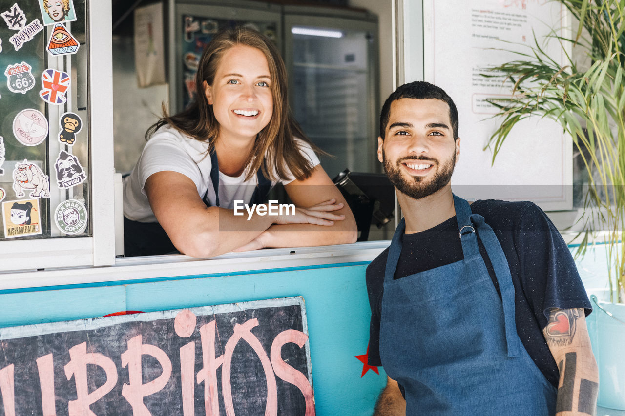 Portrait of smiling young male and female salesman at concession stand
