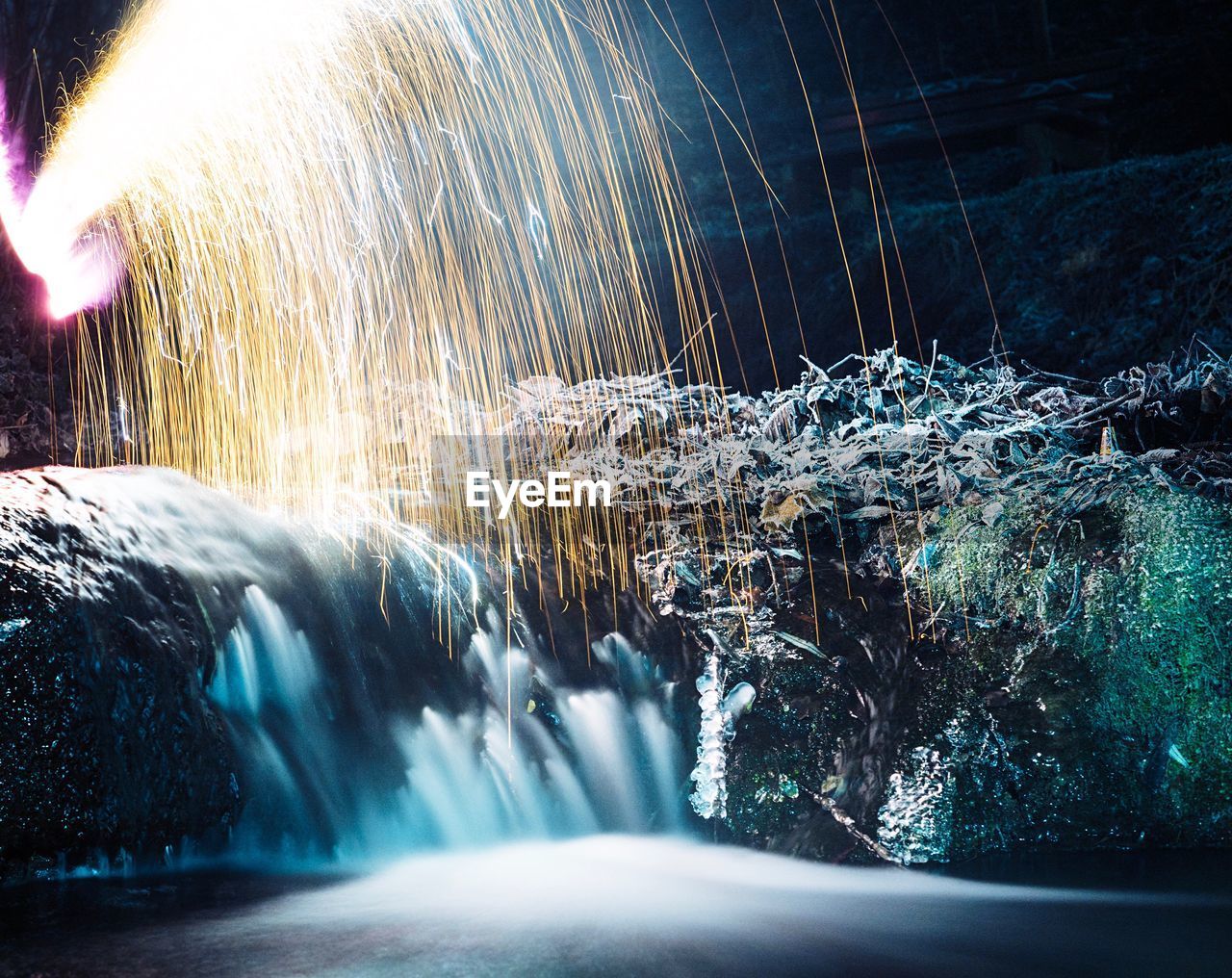 Firework display over waterfall at night