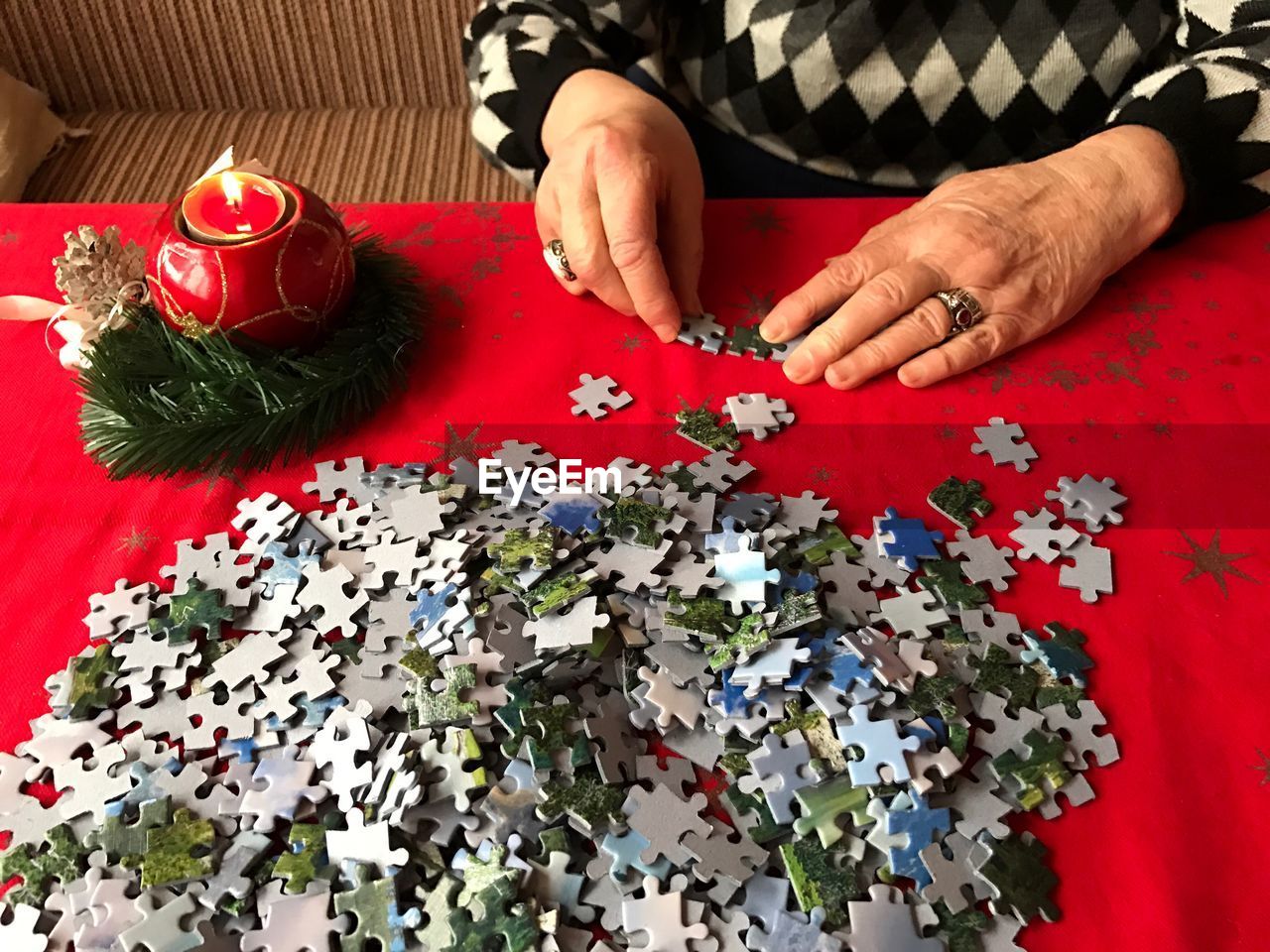 Midsection of woman assembling jigsaw puzzle pieces on table