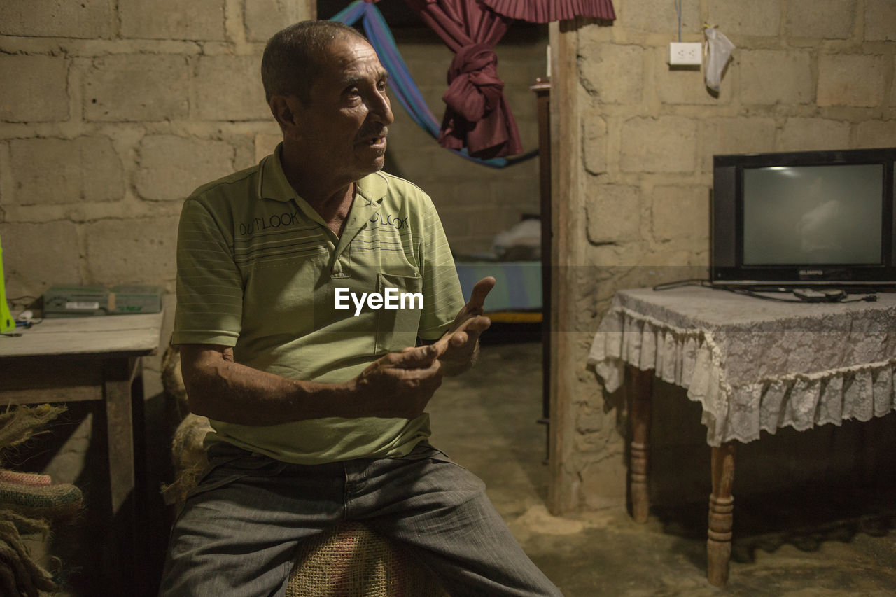 REAR VIEW OF MAN SITTING ON SOFA AT HOME