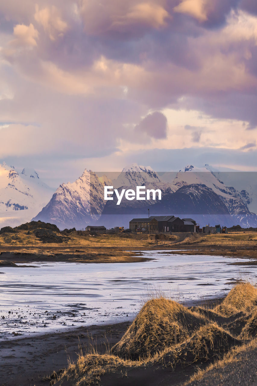 Scenic view of rocky mountains with snow in winter near stockness beach under cloudy sky in iceland