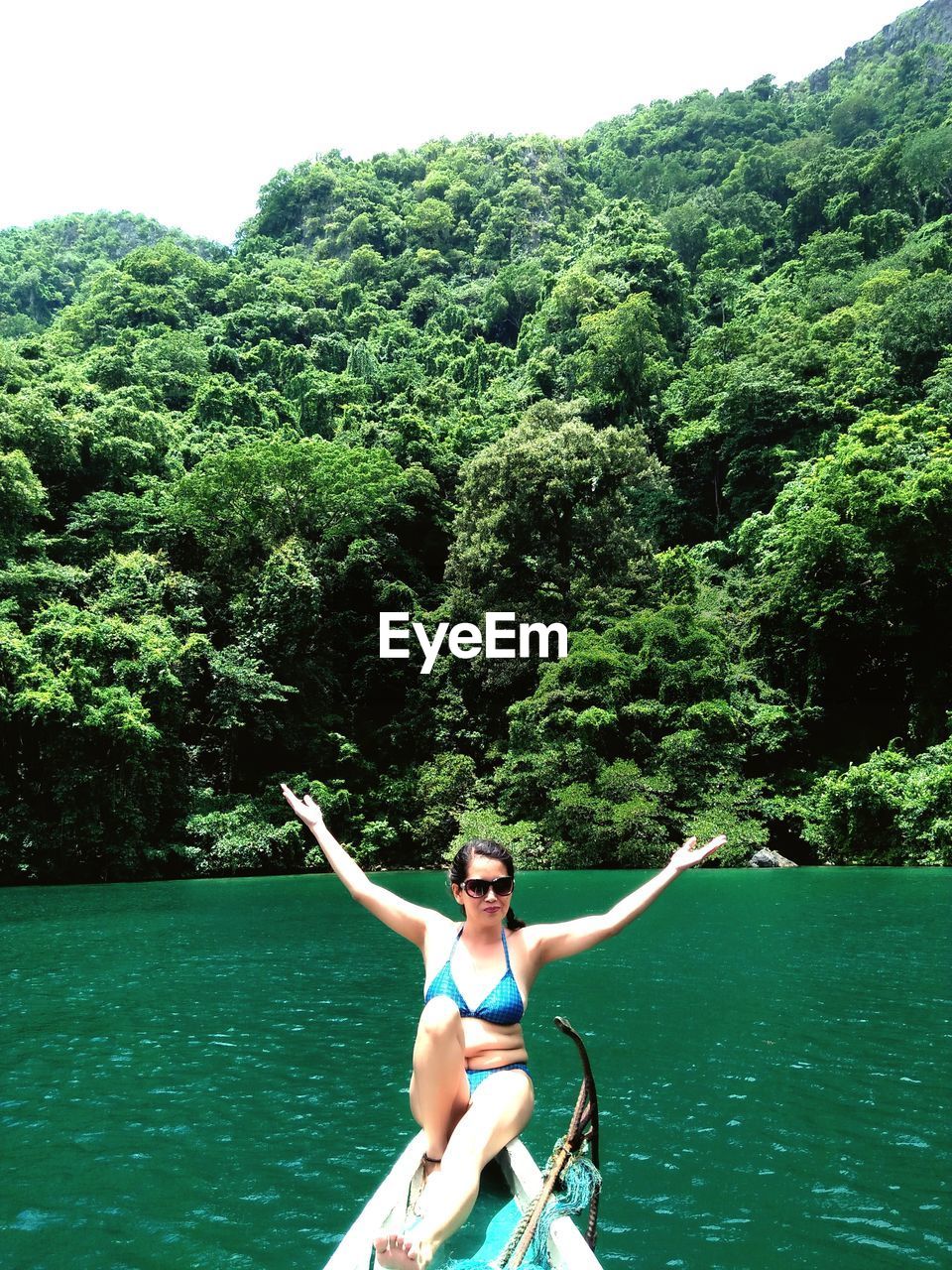 FULL LENGTH OF YOUNG WOMAN IN BOAT ON TREE