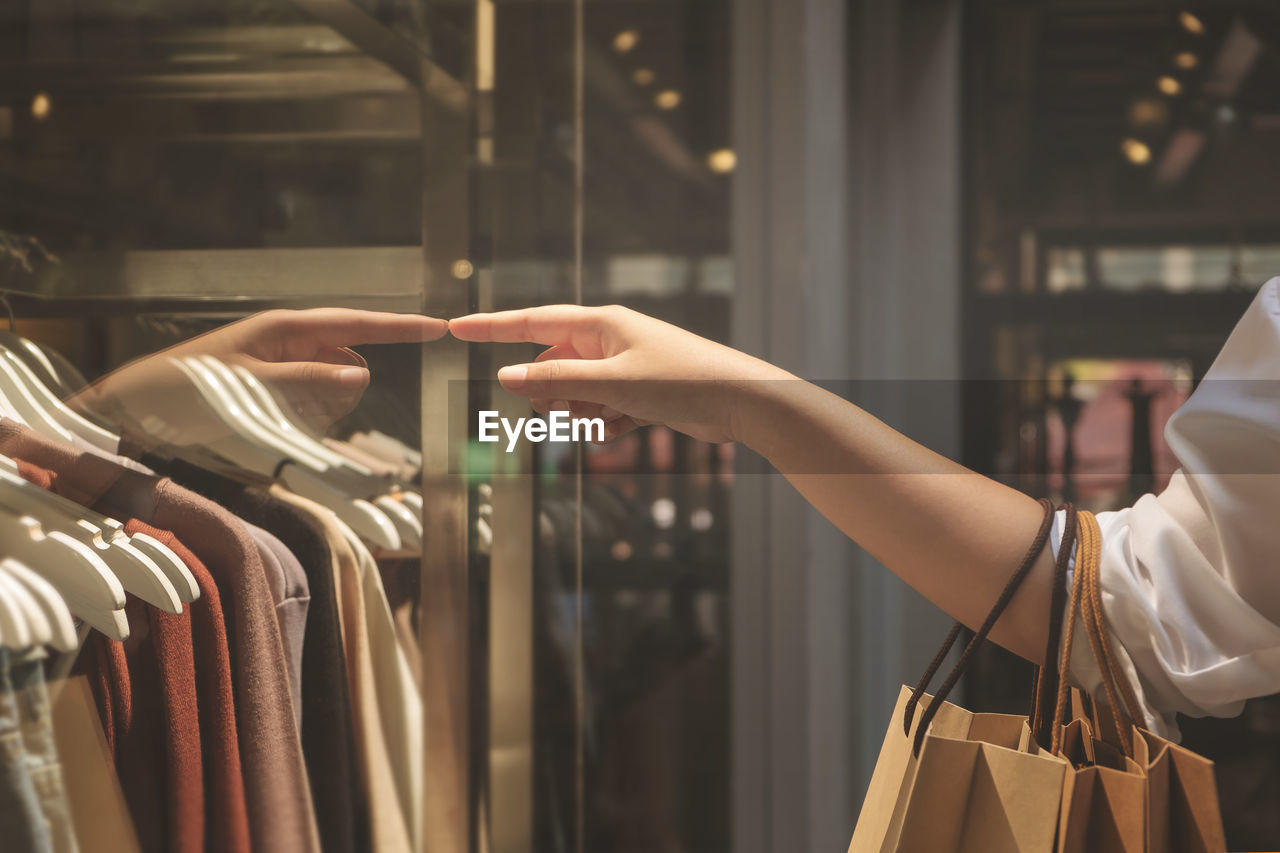 MIDSECTION OF WOMAN STANDING BY STORE