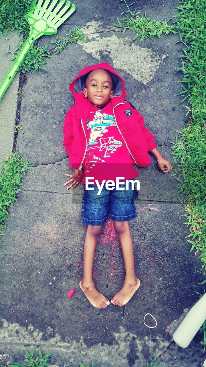 Portrait of boy lying on walkway in yard