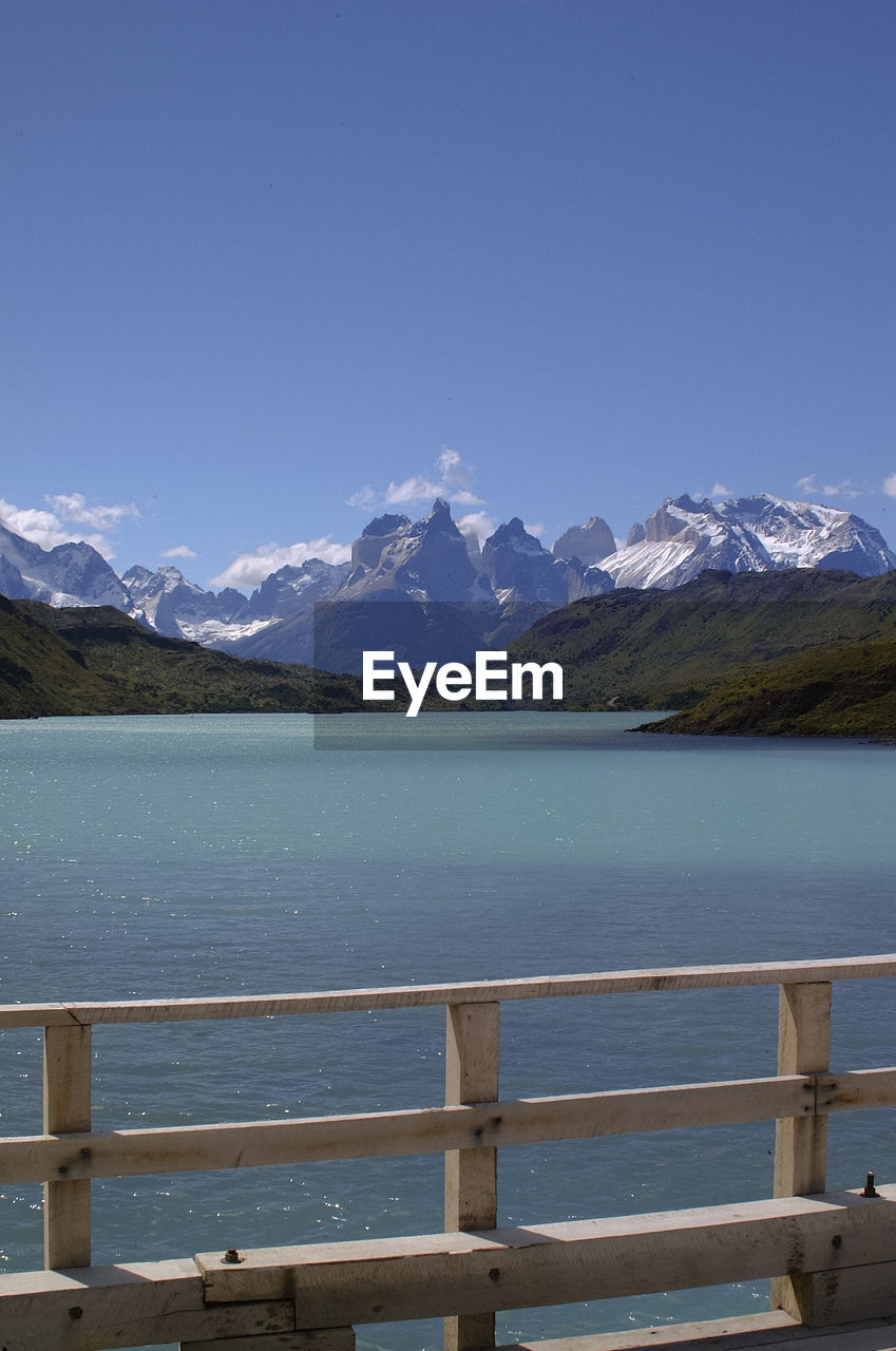 Scenic view of lake and snowcapped mountains against blue sky