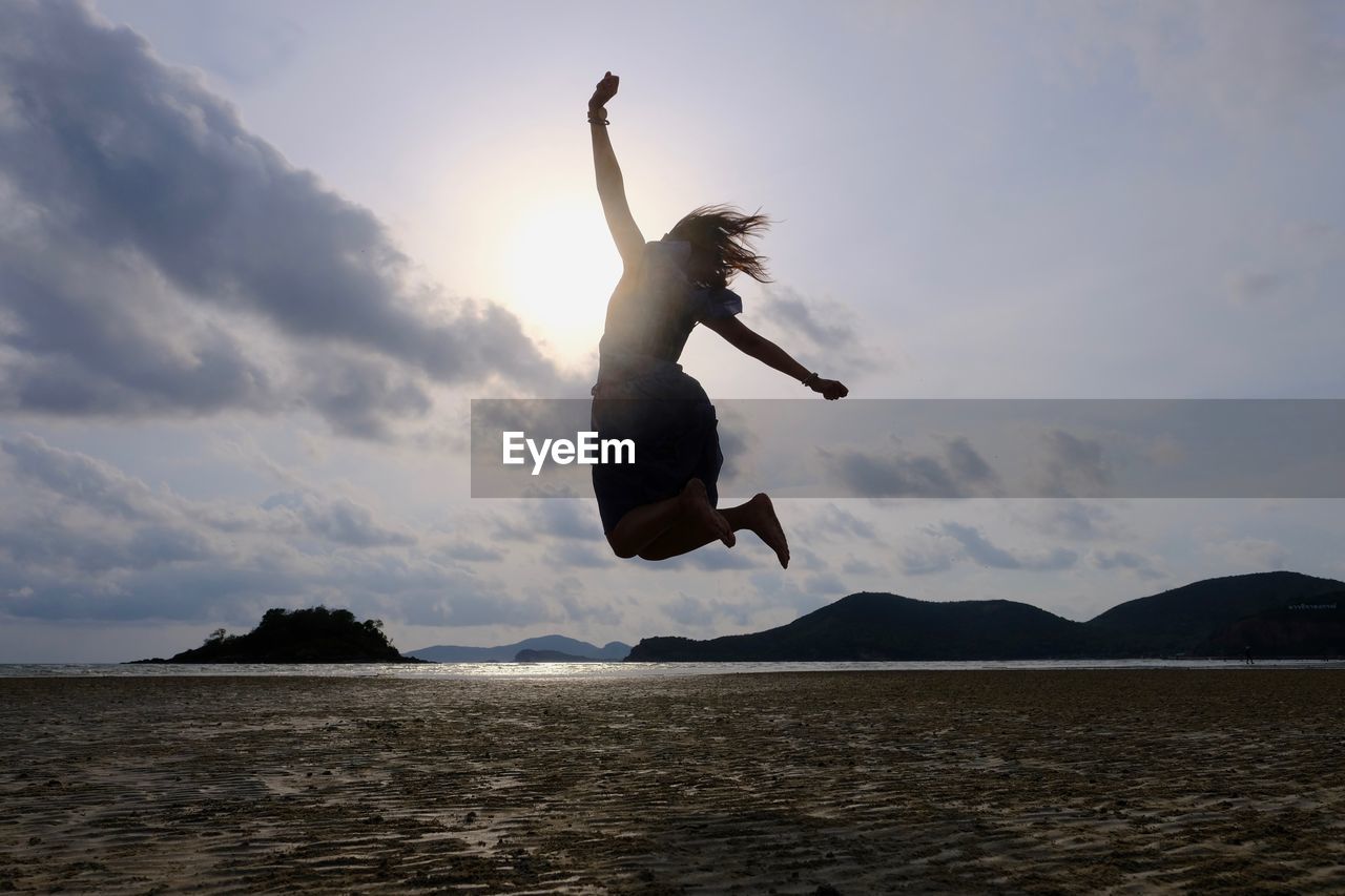 LOW ANGLE VIEW OF SILHOUETTE MAN JUMPING IN SEA AGAINST SKY