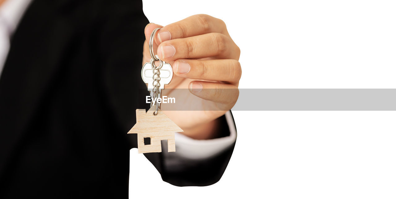 Hand of a woman holding a wooden model house showing to the front.