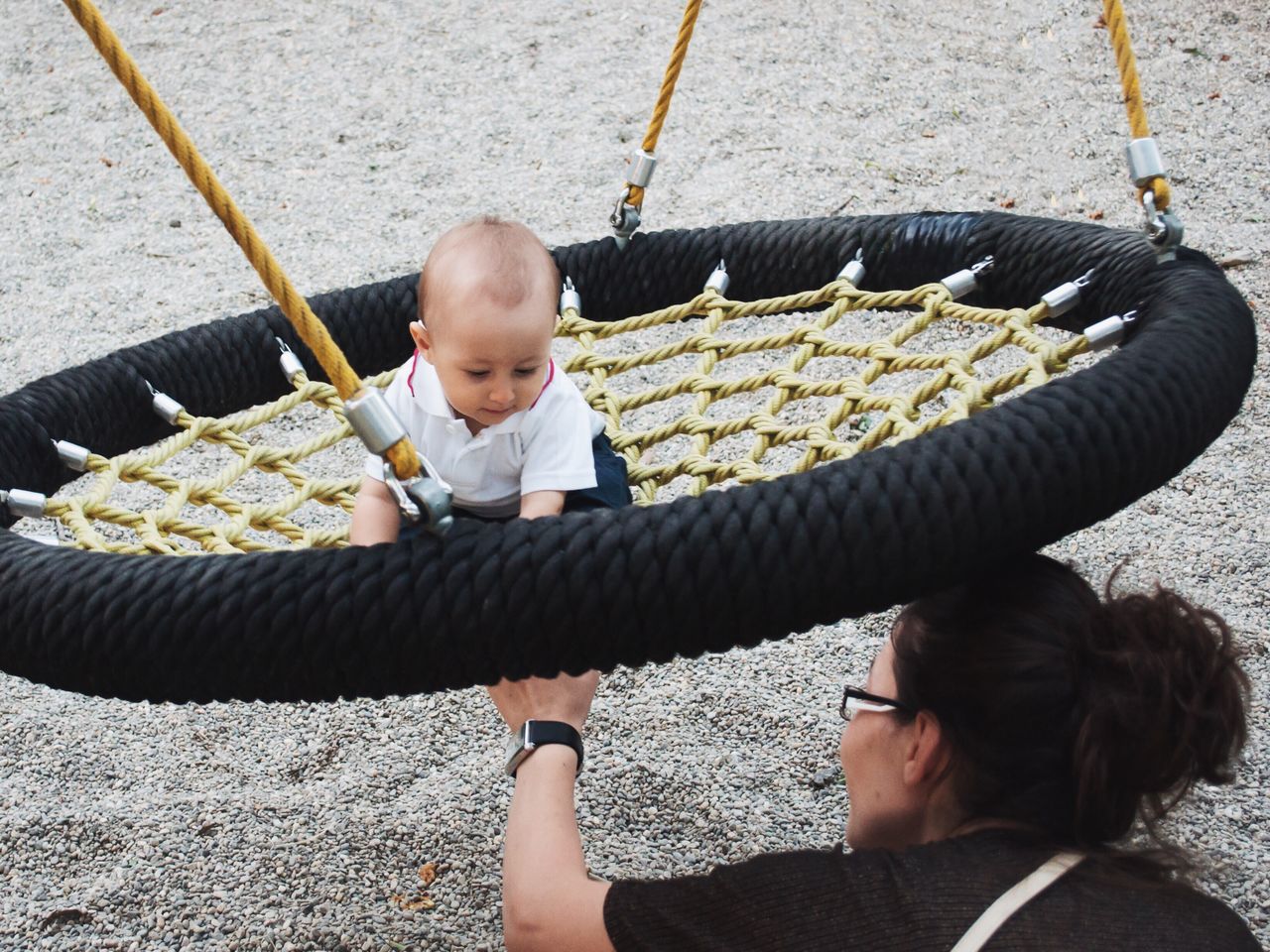 Mother examining circle rope swing in playground