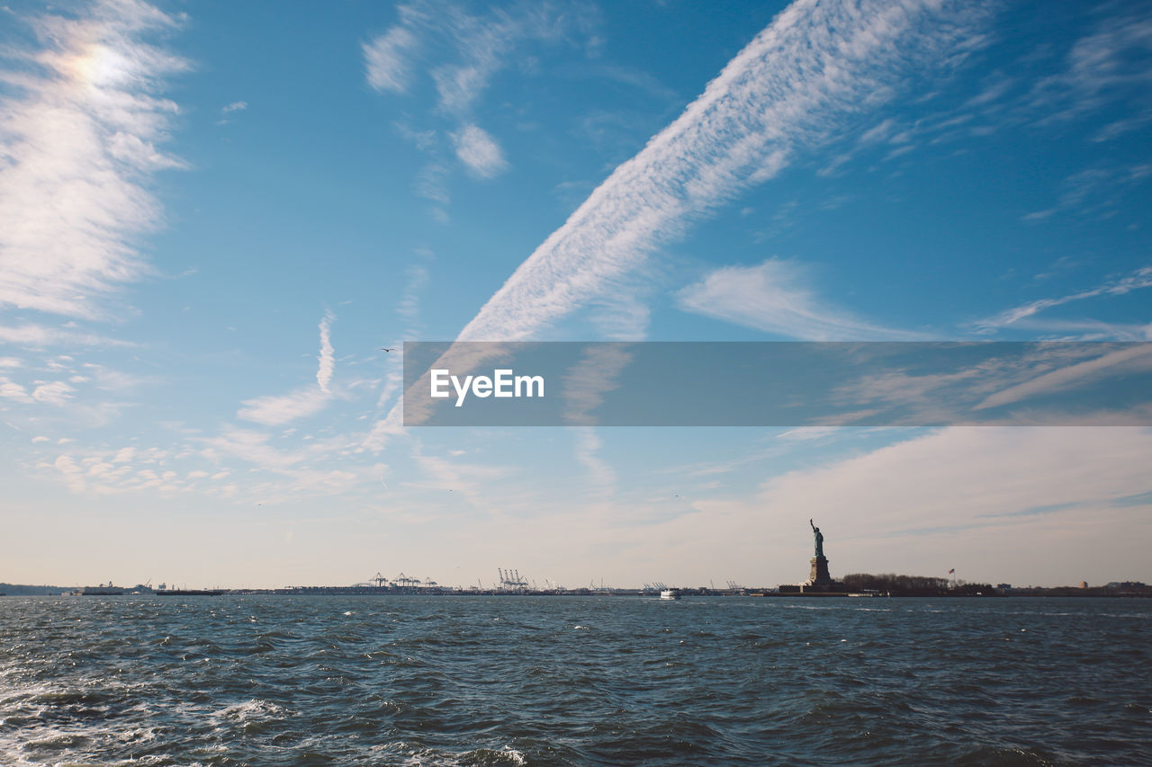 Statue of liberty by hudson river against sky