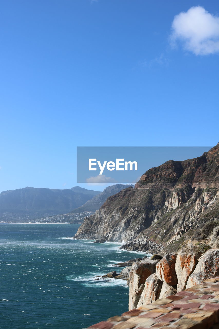 Scenic view of sea and mountains against blue sky