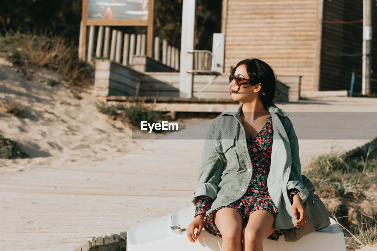 portrait of young woman wearing sunglasses while standing on footpath