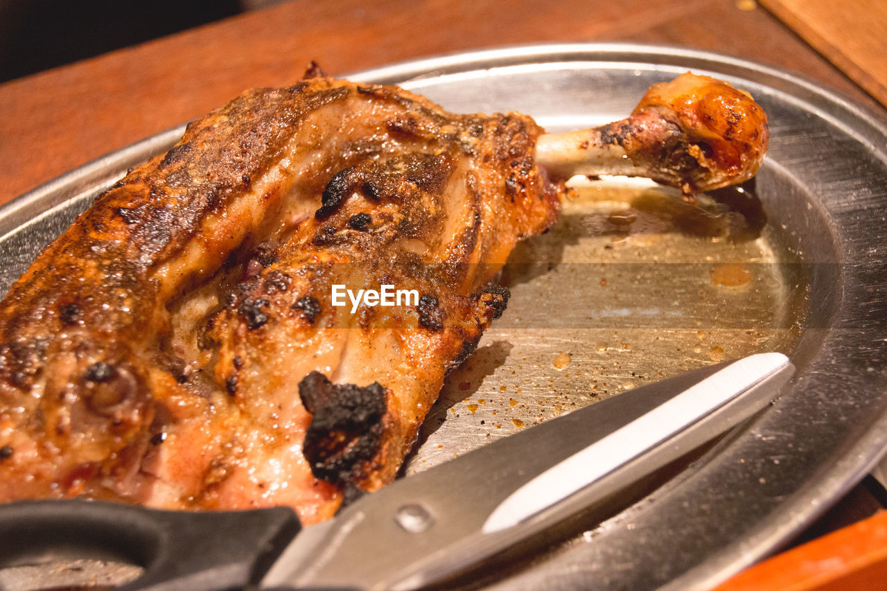 Close-up of roast chicken with pair of scissors