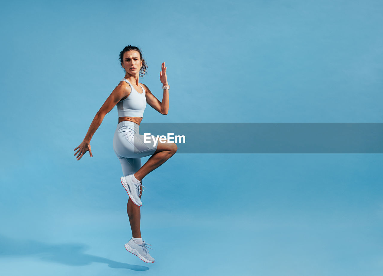 Determined athlete exercising against blue background