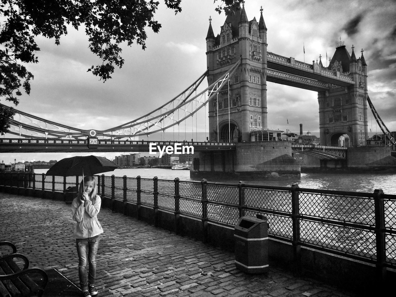Girl with umbrella standing by tower bridge
