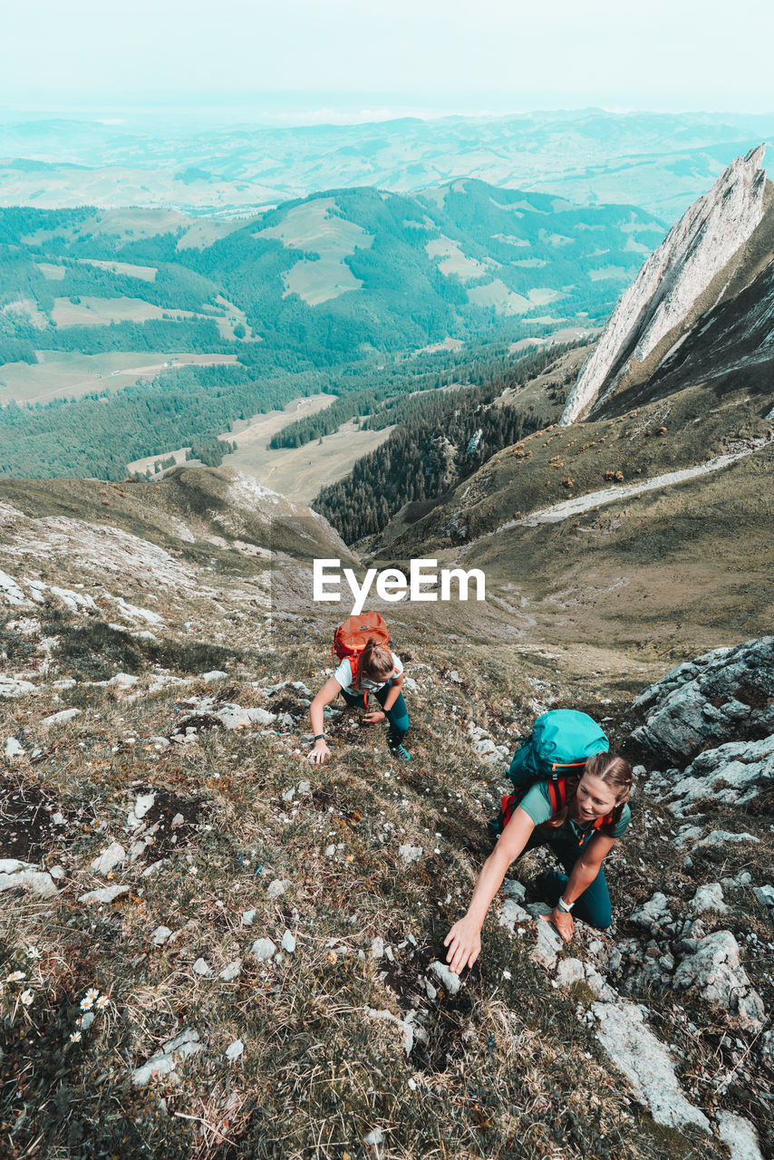 Front shot of women ascending steep cliff in swiss alps