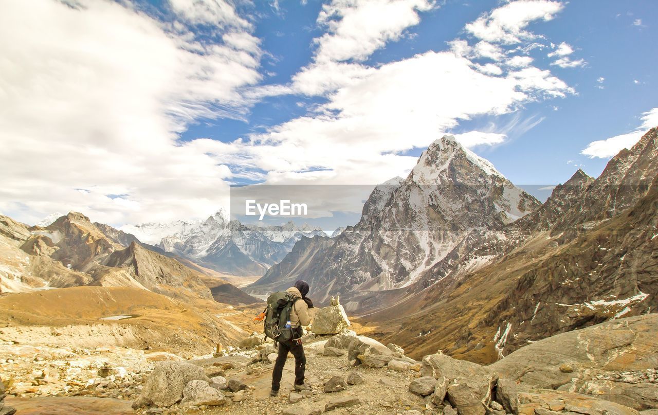 Rear view of backpacker walking on mountain against sky