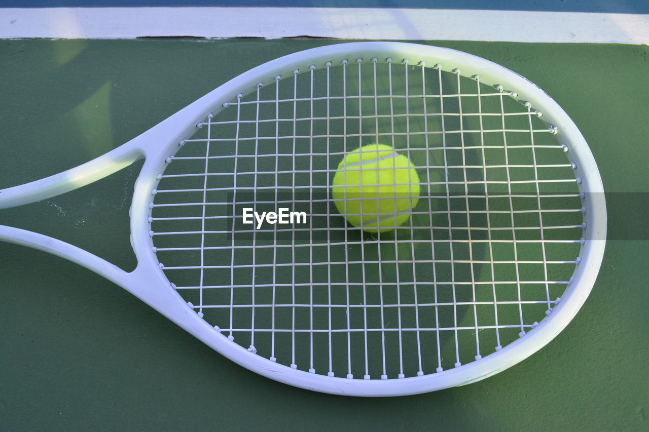 Directly above shot of ball on tennis racket at sports court