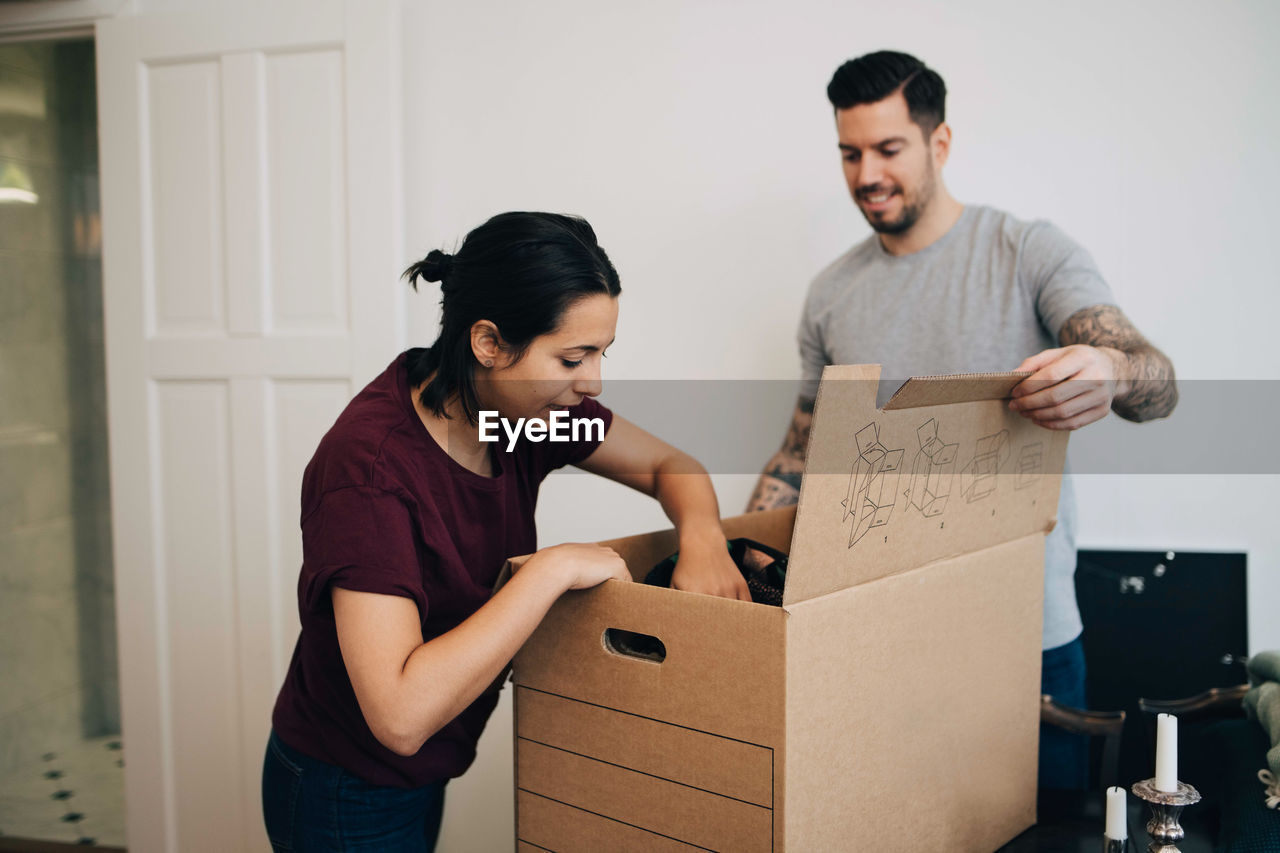 Man assisting woman in unpacking box at new house