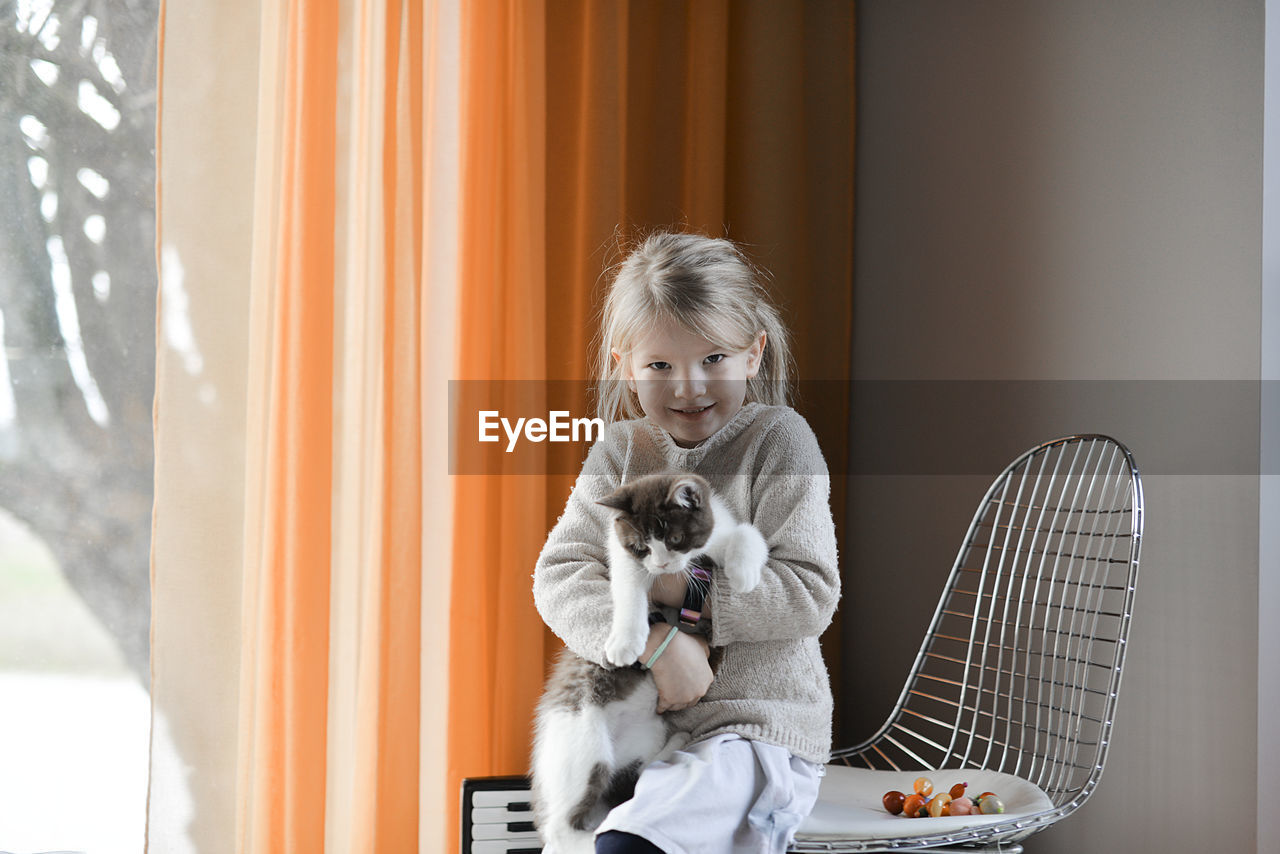 A cute little girl playing with a cat at home